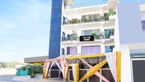 A multi-story hotel with balconies, a sign indicating it is a hotel, and a decorative archway. - Cozy Stays Near Doon University, Dehradun (Dehradun)