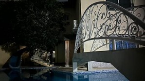 A swimming pool with a metal railing and a staircase leading to a building. - Chateau Mbeka'a Paris (Kribi)