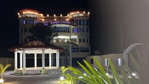 A well-lit building with a central pavilion and a balcony. - Chateau Mbeka'a Paris (Kribi)