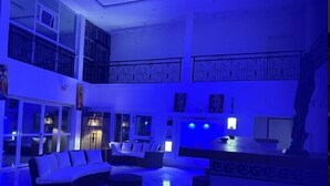 A spacious, multi-level living area with a modern design, featuring a large sofa set, a dining table, and a decorative statue. - Chateau Mbeka'a Paris (Kribi)