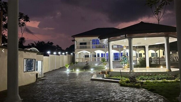 A two-story building with a covered patio area, a staircase leading to the upper level, and a well-lit entrance. - Chateau Mbeka'a Paris (Kribi)