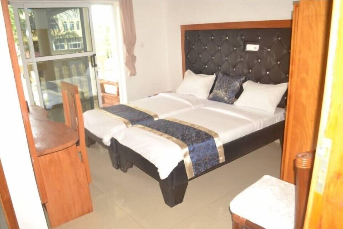 A double bed with a dark headboard, white and blue bedding, and a wooden chair beside it.
