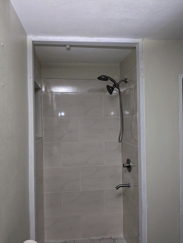 Un espacio de ducha pequeño y cerrado, con paredes de azulejos y ducha.