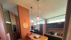 Une cuisine moderne dotée d’un îlot central, de luminaires suspendus et donnant sur la salle à manger.