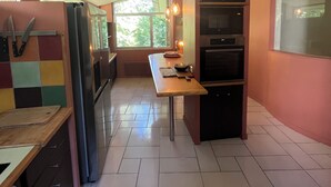 Une cuisine avec un long plan de travail, un réfrigérateur et un four à micro-ondes.
