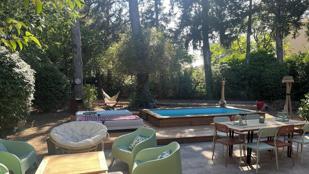 Une terrasse extérieure avec une piscine, entourée de verdure.