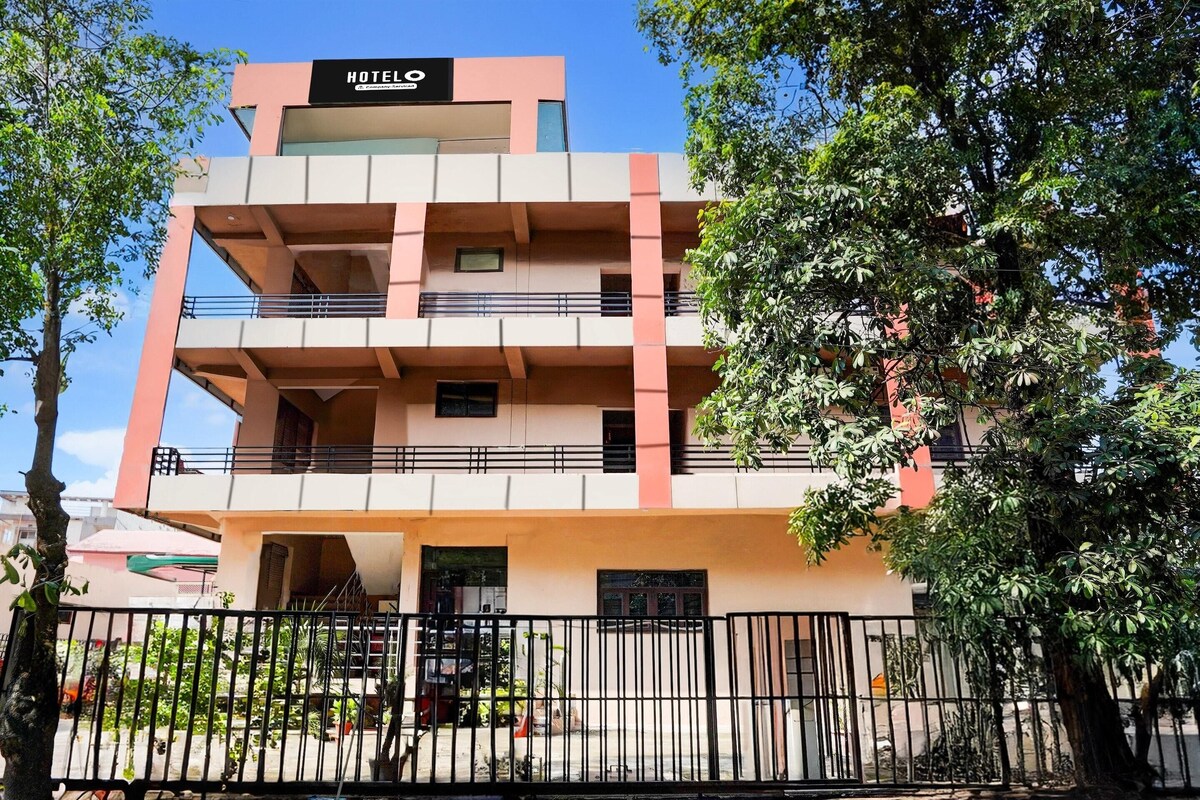 A multi-story hotel with a pink and white facade, balconies, and a sign indicating it is a hotel.