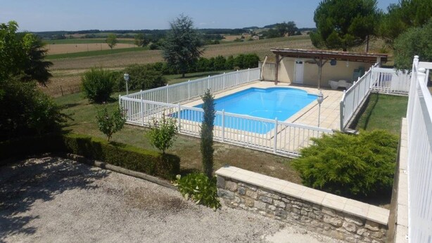 A rectangular swimming pool with a white fence, surrounded by a stone wall and a grassy area. - Spacious Holiday Home in Monsegur With Pool (Monsegur)