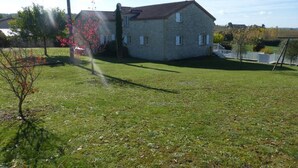 A stone building with a sloped roof, surrounded by a grassy yard and a white fence. - Spacious Holiday Home in Monsegur With Pool (Monsegur)