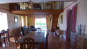 A dining area with a long table, chairs, and a staircase leading to an upper level. - Spacious Holiday Home in Monsegur With Pool (Monsegur)