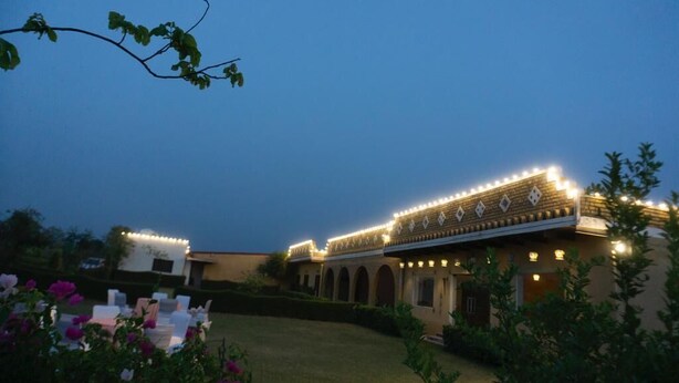 A building with a traditional architectural style, featuring arched doorways and a series of lights along the roofline. - Sultanpur Resorts (Gurugram)