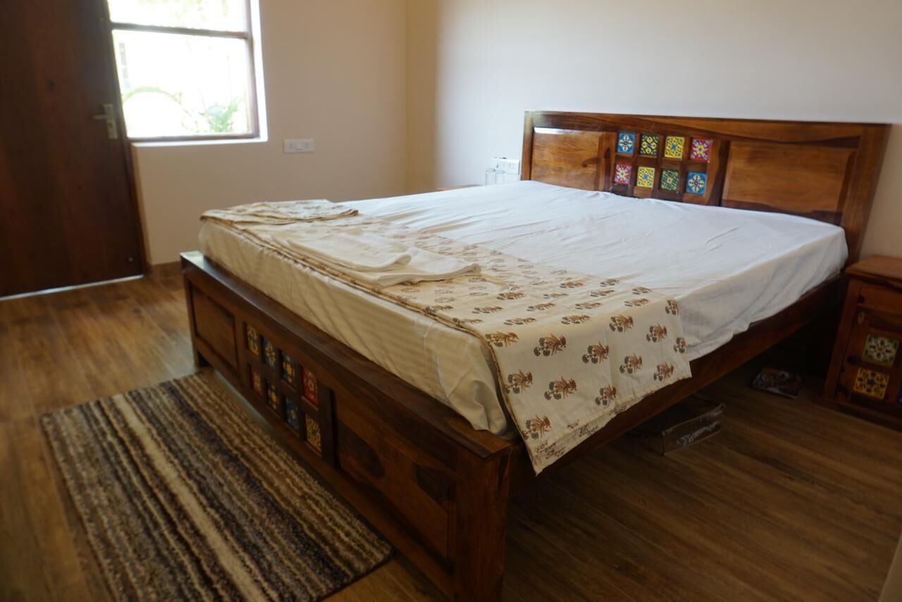 Une chambre avec un lit en bois, une fenêtre et un plancher en bois.