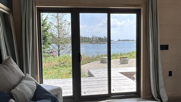 Een slaapkamer met een groot bed, uitzicht op een meer en een houten terras buiten.