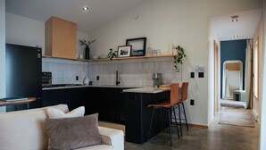 Een moderne keuken met een centraal eiland, een eetgedeelte met stoelen en een bank met kussens.