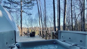 A hot tub with a stone exterior, surrounded by trees and a wooden deck.