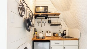 Une cuisine compacte équipée d’un réfrigérateur Galanz, d’un four à micro-ondes et d’une bouilloire posés sur le plan de travail.