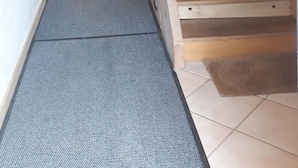 Een houten trap met een bekleed plateau dat leidt naar een kamer met een deur.