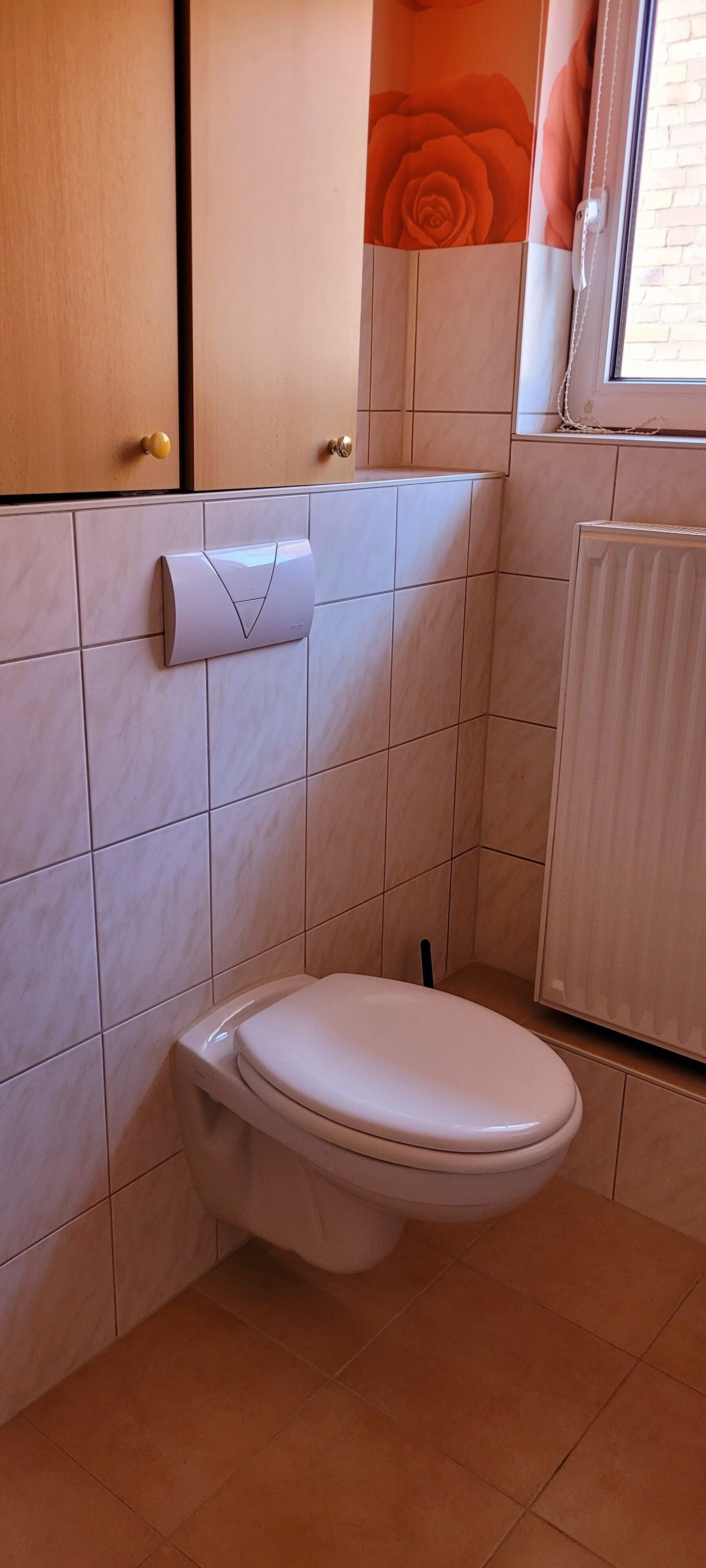 A bathroom with a toilet, a towel dispenser, and a radiator.