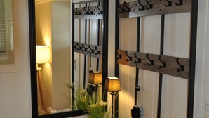 Un couloir avec un banc en bois, un miroir et un porte-manteau fixé au mur.
