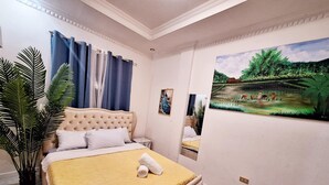 Une chambre avec un grand lit, un miroir et un tableau accroché au mur.