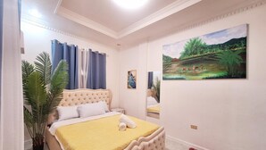Une chambre avec un grand lit, un tableau accroché au mur et une plante en pot.