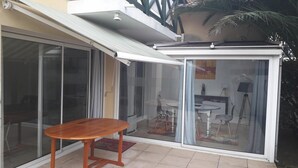 Un patio couvert avec une porte-fenêtre coulissante donnant sur un espace intérieur.