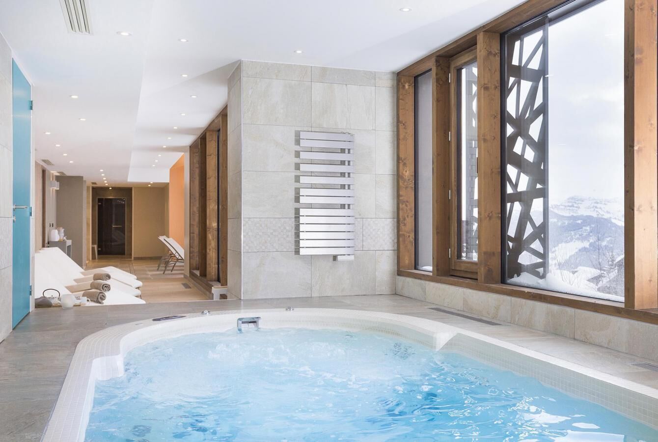 A modern indoor swimming pool with a view of snow-capped mountains through large windows.