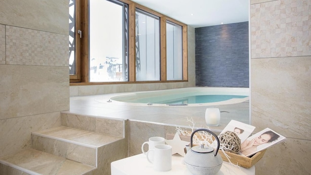 A modern bathroom with a large window, a bathtub, and a small table with toiletries. - Wifi, ski-in/ski-out & foot of the slopes, swimming pool, hammam, terrace, balcony, tv, ski locker (Les Saisies)