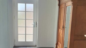 A room with a large wooden wardrobe, a white door with frosted glass panels, and a tiled floor. - Vacation apartment Weinstraßenmitte (Neustadt an der Weinstraße)