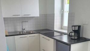 A modern kitchen with white cabinets, a black countertop, and a coffee maker. - Vacation apartment Weinstraßenmitte (Neustadt an der Weinstraße)