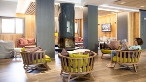 A cozy lounge area with wooden furniture and a central fireplace. - Apartment in Tignes With Ski-in/ski-out Access (Tignes)
