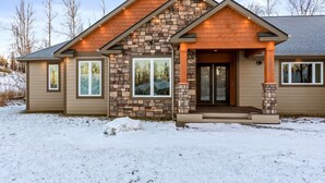 A modern house with a stone facade, large windows, and a covered entryway. - The Dreamland House - Central, Stylish, Spacious (Wasilla)