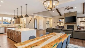 A spacious kitchen with a central island, pendant lighting, and a large dining table with chairs. - The Dreamland House - Central, Stylish, Spacious (Wasilla)
