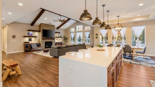 A spacious kitchen with a large island, a built-in fireplace, and a dining area with a view of the outdoors. - The Dreamland House - Central, Stylish, Spacious (Wasilla)