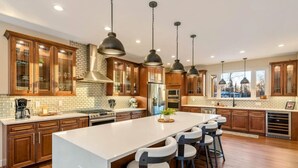 A spacious kitchen with a large island, wooden cabinets, and pendant lighting. - The Dreamland House - Central, Stylish, Spacious (Wasilla)