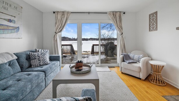 A living room with a sofa, armchair, coffee table, and a view of a deck and outdoor area. - Charming 2-bedroom Lake House Directly on Cross Lake (Salem Lakes)