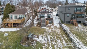 A residential area with houses, a wooden deck, and a snow-covered lawn. - Charming 2-bedroom Lake House Directly on Cross Lake (Salem Lakes)