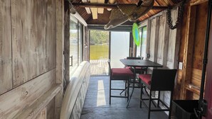 Een houten interieur met een tafel, stoelen, een bankje en uitzicht op de omgeving.
