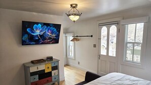 Een slaapkamer met een bed, een dressoir, een televisie en een raam met uitzicht.