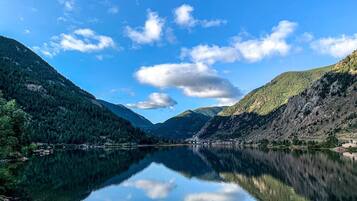 Un llac tranquil envoltat de muntanyes boscoses sota un cel serè.