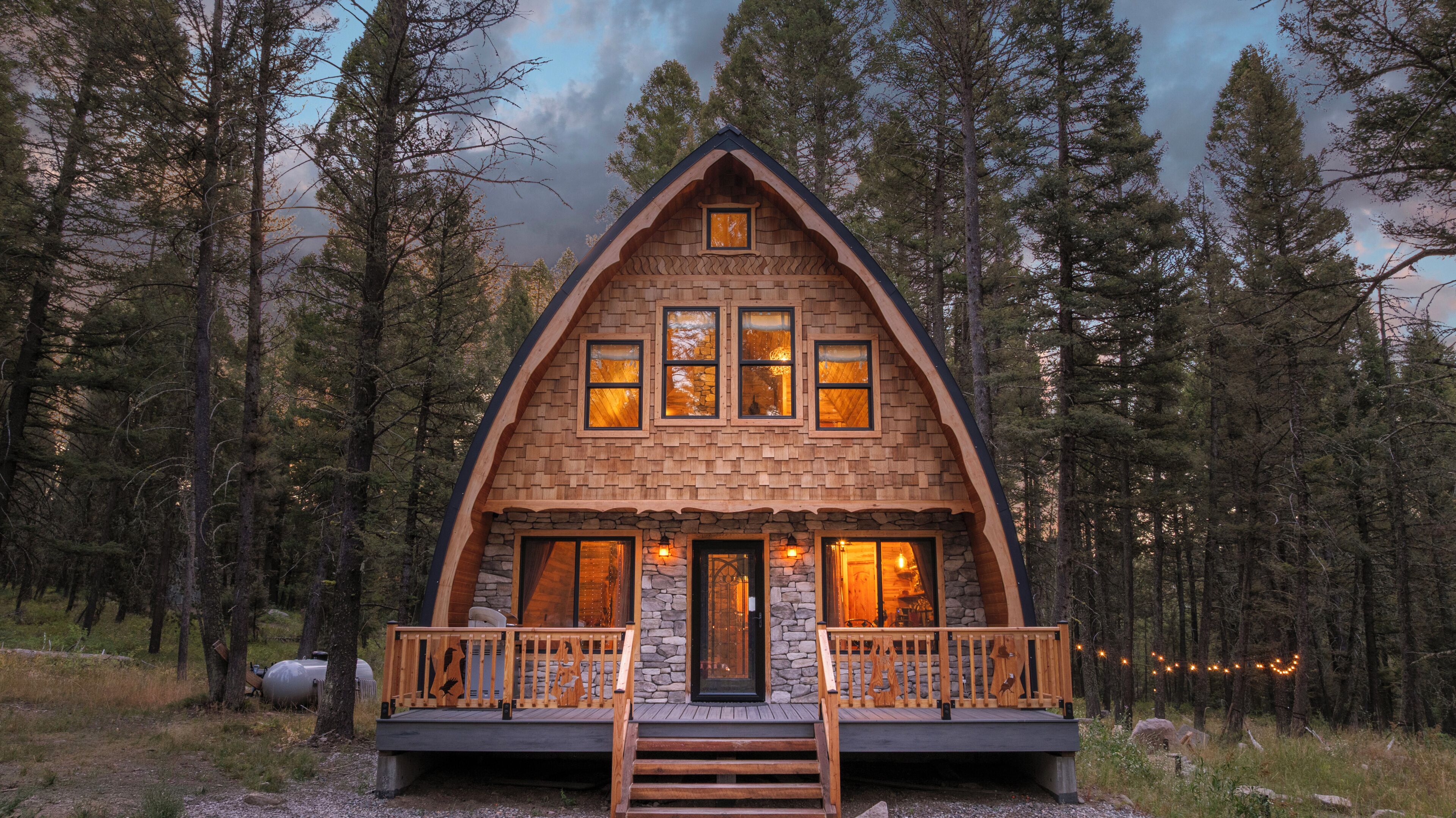Eine Holzhütte mit Steinunterbau, Holzverkleidung und einer Holzterrasse mit Geländer.