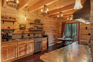Interno di una baita in legno con angolo cottura, sala da pranzo e una grande finestra.