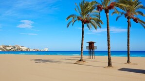 A beach with palm trees and a lifeguard tower. - Apartamento Comodo Cerca de la playa (Conil de la Frontera)