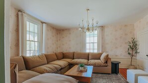 A living room with a sectional sofa, a wooden coffee table, and a chandelier. - Branch and Barrel: Hot Tub & Sauna + Mtn Views (Roseland)