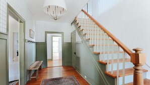 A hallway with a wooden staircase, a bench, and a patterned rug. - Branch and Barrel: Hot Tub & Sauna + Mtn Views (Roseland)
