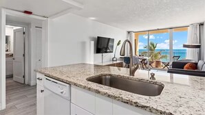 Een moderne keuken met een granieten aanrechtblad, een roestvrijstalen spoelbak en witte kastjes.