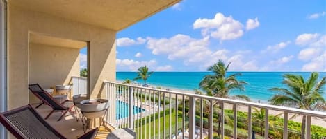 Ein Balkon mit Blick auf das Meer, ein Pool und Palmen.