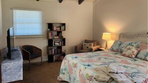A bedroom with a bed, a chair, a desk, a bookshelf, and a ceiling fan. - 3-bedroom, 2-bathroom beach getaway Tranquil Waves, Jekyll Island (Jekyll Island)