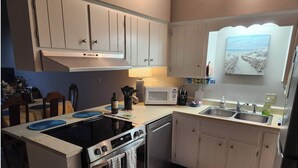 A modern kitchen with white cabinets, a black stove, a microwave, and a sink. - 3-bedroom, 2-bathroom beach getaway Tranquil Waves, Jekyll Island (Jekyll Island)