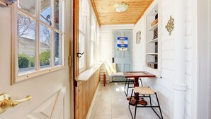 A narrow hallway with a wooden ceiling, a bench, a table, and a door with a window. - Charming 3-bedroom farmhouse with AC, WiFi,  5 minutes to Sea Isle Beaches! (Dennis)